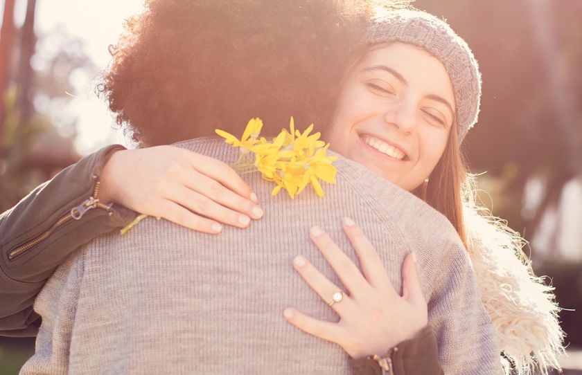 two women hugging, yellow flower, diamond ring